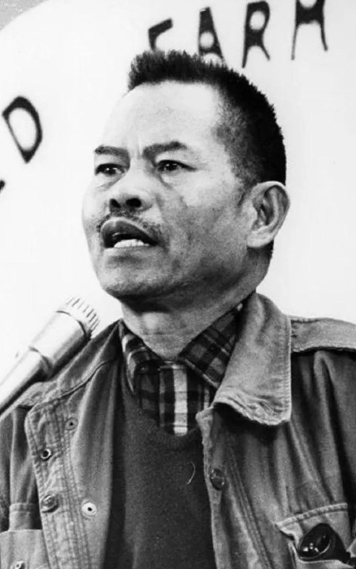 Historic black-and-white photo of Filipino American labor leader Larry Itliong speaking into a microphone. A key figure in the Delano Grape Strike, Itliong united Filipino and Mexican farmworkers in the 1960s and helped shape multiracial labor organizing in the U.S.